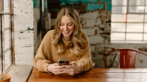 Une femme assise à une table regarde la photo de son téléphone portable